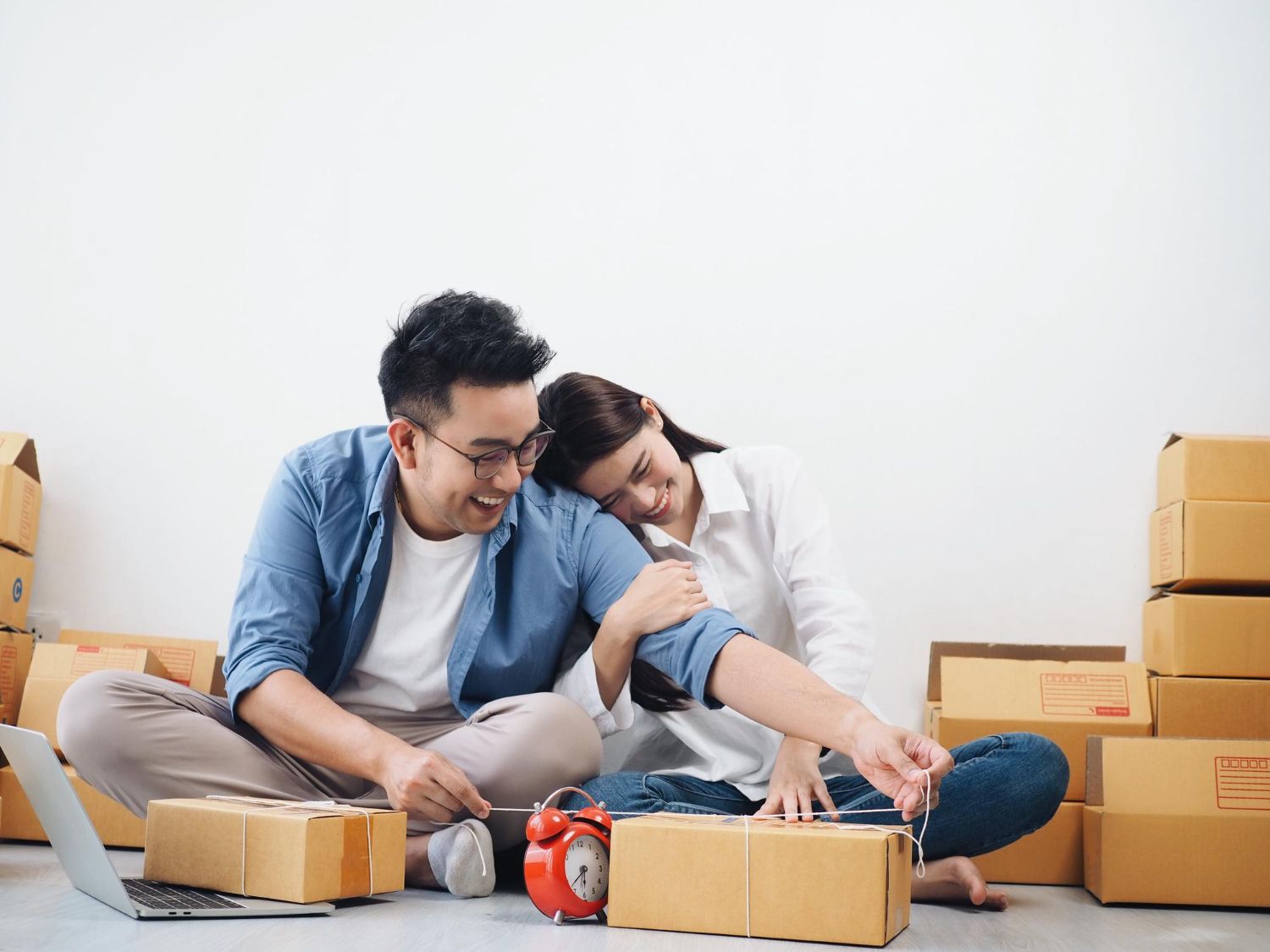 A newlywed couple sitting on the floor with moving boxes, preparing to begin marriage counselling in Singapore.